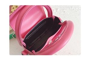 Gros plan d'un mini sac rose avec doublure noire et détails de bandoulière verte
