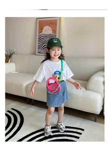 Fillette avec un mini sac bandoulière rose vif à chaîne verte et une jupe en denim bleu