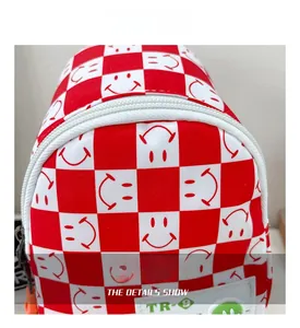 Détail du sac bandoulière enfant à damier rouge et blanc avec smiley et zip en résine