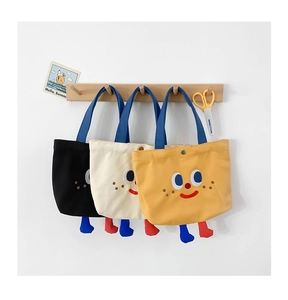 Close-up of cute cartoon canvas mini tote bags in black, white, and yellow colors