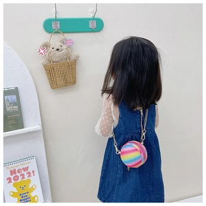 Detail of colorful sequin round kids crossbody bag with golden chain strap on model