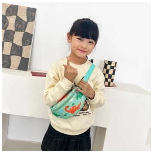 Détail du sac bandoulière enfant vert menthe avec motifs dinosaures sur une fille