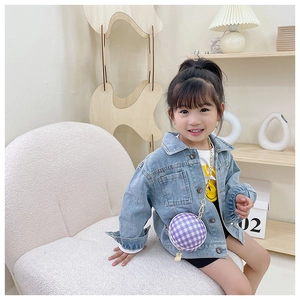 Detail of child wearing blue denim jacket and purple plaid round crossbody bag with rabbit charm