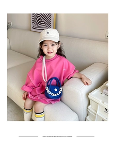 Détail d'un mini sac bleu à chaîne blanche porté avec un t-shirt rose pour enfant