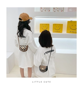 Detail showing kids plaid saddle bag with metal lock and white printed cotton t-shirt