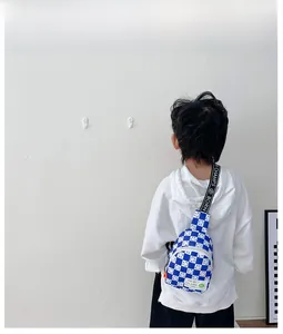 Sac bandoulière enfant à damier bleu avec motif sourire porté par un enfant