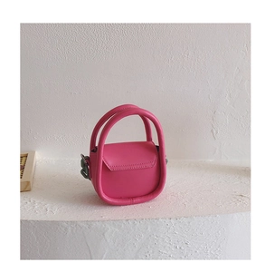 Détail d'un mini sac à main rose vif avec une chaîne en résine vert olive pour fille