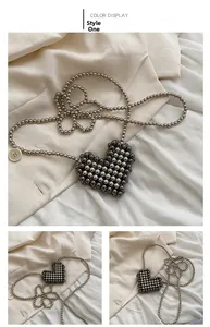 Detail of a dark grey metallic beaded heart-shaped mini bag with a long bead chain strap