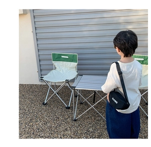 Détail d'un enfant portant un sac bandoulière noir avec texte GAME en scène de camping