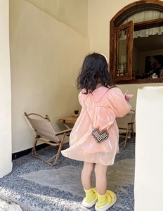 Detail of pink organza girl dress featuring a large collar and pearl heart crossbody bag