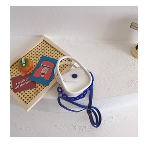 Détail du mini sac blanc avec chaîne bleue épaisse et boucle de bouton ronde contrastée