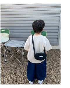 Détail d'un sac bandoulière en toile noire avec lettrage GAME blanc pour style enfant