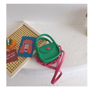 Gros plan du sac selle vert avec chaîne rose dans une mise en scène créative