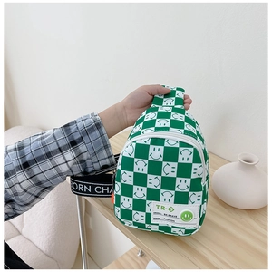 Détail du sac de poitrine à damier vert avec smileys blancs et bandoulière à lettres
