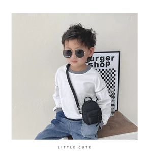 Close-up of a mini black nylon crossbody bag on a child model with an adjustable strap