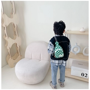 Vue arrière d'un enfant portant un sac à bandoulière damier vert avec motif sourire