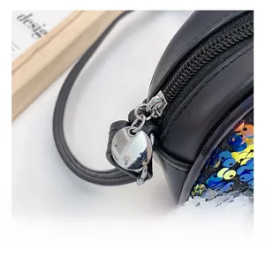 Macro shot of polished round metal zipper pull on black sequin crossbody bag