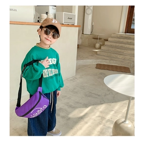Detail of a purple canvas chest bag for boys paired with a green sweatshirt and jeans
