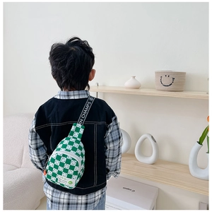 Détail du sac de poitrine enfant à damier vert et blanc avec motifs souriants