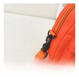 Detail view of durable black plastic buckle and orange canvas strap on lightweight bag