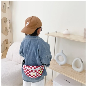 Detail view of red checkered canvas chest bag for kids with neon green zipper accents