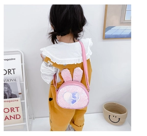 Pink sequin bunny ear crossbody bag with heart patch shown on child model back view