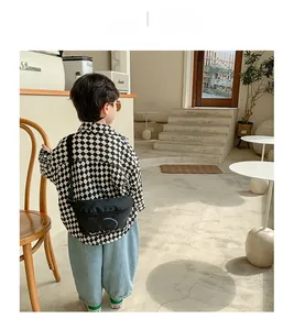 Street style detail of a boys casual black nylon chest bag with trendy letter printing