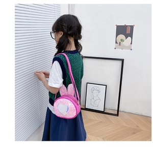 Pink sequin crossbody bag with Elsa print and rabbit ears worn by child model