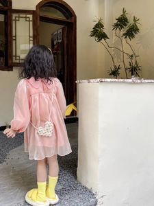 Detailed view of kids pink tulle dress paired with a pearl heart-shaped crossbody bag