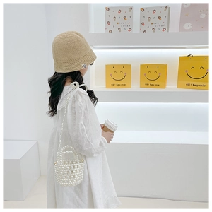 Detailed view of child handmade pearl woven crossbody bag with cute smiley charm