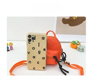 Detailed comparison view of orange mini canvas crossbody bag next to a smartphone