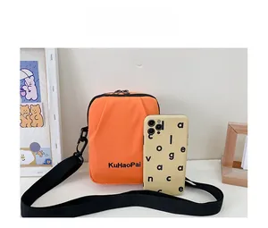 Detailed comparison showing small orange canvas crossbody bag size next to a smartphone