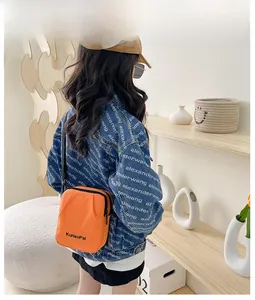 Detail view of bright orange canvas messenger bag with zipper and logo print for kids