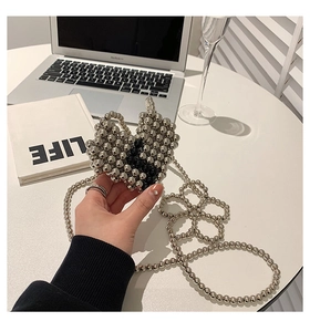 Detail of handmade heart-shaped silver beaded mini bag with pearls and long chain strap