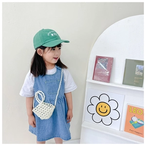 Detailed view of child fashion outfit featuring handmade white pearl beaded crossbody bag