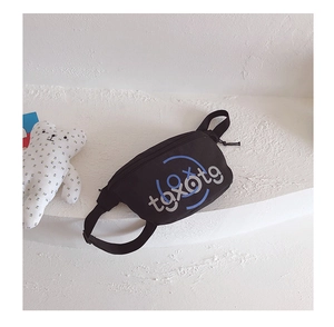 Detail of black canvas boy chest bag with blue-gray letter print on minimalist surface