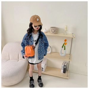 Detail of trendy orange canvas crossbody bag paired with a printed blue denim jacket