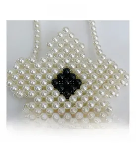 Close-up of handmade white pearl beaded flower bag with black center and beaded strap