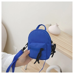 Close-up of mini bright blue canvas crossbody bag with zippers shown in a hand
