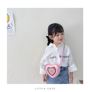 Close-up of pink heart-shaped crossbody bag with sparkling multi-color sequins on toddler