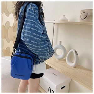 Detail of blue nylon crossbody bag for kids with durable zippers and adjustable strap
