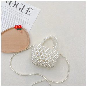 Flat lay view of white pearl beaded mini bag with cross-body strap and Vogue magazine decor