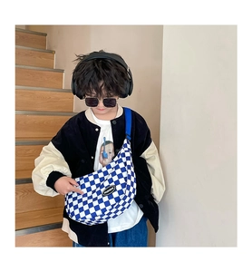 Detail of blue checkerboard canvas crossbody bag with adjustable strap and logo for kids