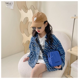 Close-up of a blue nylon crossbody bag on a street style denim jacket for kids