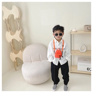 Close-up of orange mini crossbody bag with adjustable strap worn by a young boy