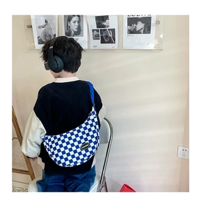Detail of blue checkerboard canvas crossbody bag with adjustable strap and fashion patch