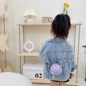 Purple checkered round crossbody bag for kids with gold chain strap shown on denim jacket
