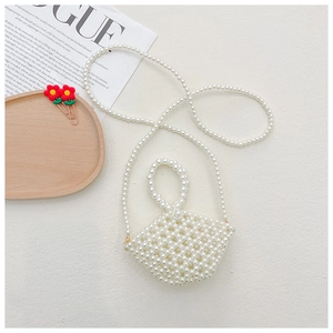 Detail of a handmade white beaded mini bag with pearls and golden metal buckles