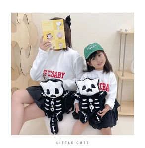 Close-up of cute black plush backpack with white skeletal cat pattern for parent-child style