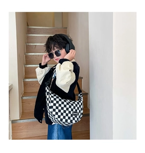 Close-up of kids checkered crossbody bag with adjustable strap on a child model
